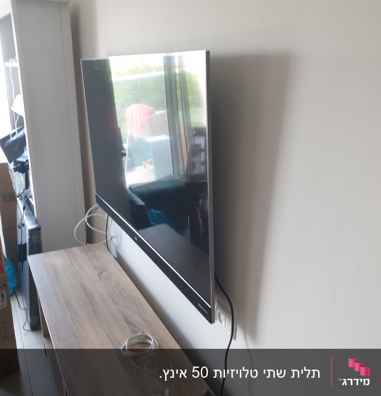 טלוויזיה תלויה על הקיר עם כבלים חשמליים